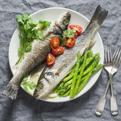 Baked sea bass with asparagus and tomatoes. Healthy diet food concept. On a gray background, top view