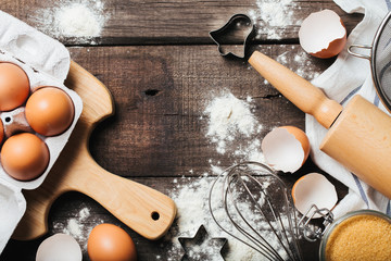 Baking or cooking wooden background with cookies molds, flour, sugar, kitchen tools and eggs, top view