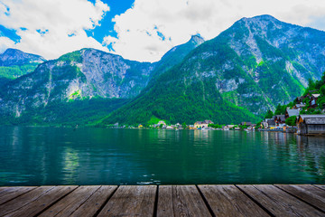 Popular beautiful village in Austria , Hallstatt in the green summer scenery and crystal clear water with the wooden plank as foreground 