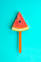 Summer watermelon slice popsicles on a blue rustic wood background.