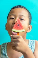 Happy asian boy summer watermelon slice popsicles on a blue rustic wood background.