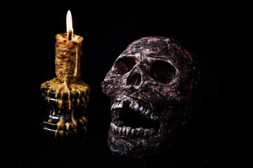 Skull and candle in black background.