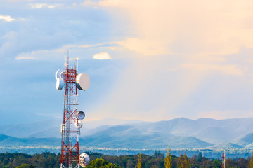 telecommunication tower with mountain range background with warm sunset light casting on clouds