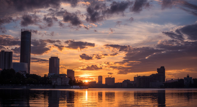 Yekaterinburg city center on sunset. City pond view, amazing clouds and sky. High buildings, skyscrapers on the embankment of the river Iset