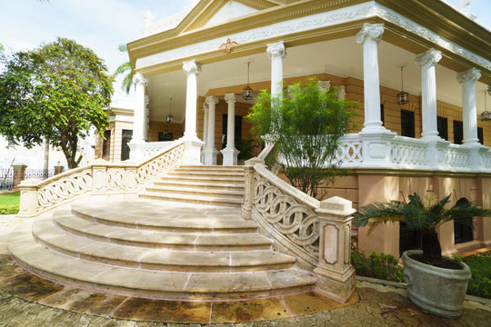 Corner facade of old rich family house with beautiful buches and summer day terrace. Huge ancient stairs to house