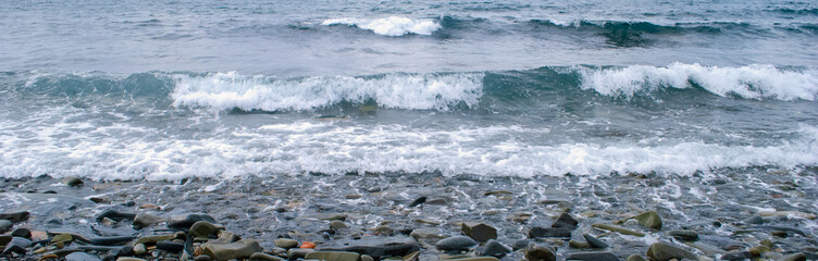 The sea waves rolling on the stony coast, a close up