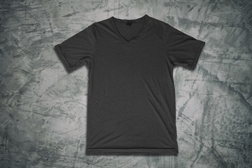 Grey t-shirt on concrete wall background.