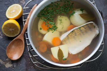 Fish soup with sudak in a metal pot, view from above, horizontal shot
