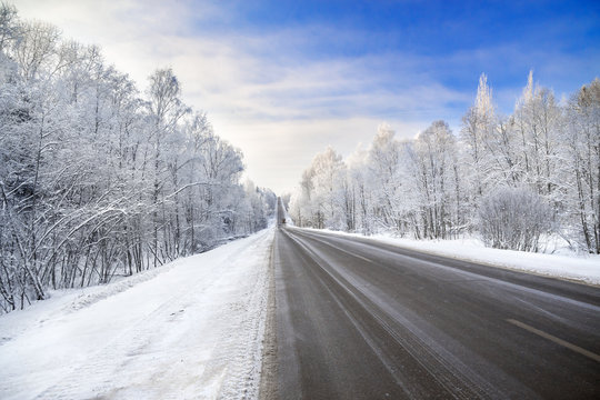 winter landscape with asphalt road,forest and blue sky