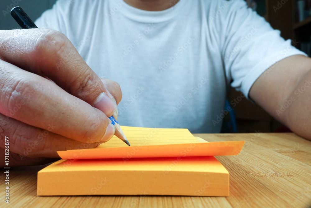 Poster hand pencil writes in a orange notepad