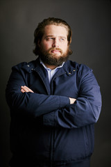 man with beard and long hair looking away arms folded