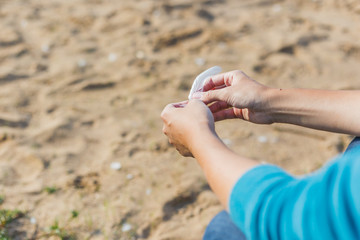 Woman holds a white feather of a seagull in hand. Symbol of lightness and fragility.