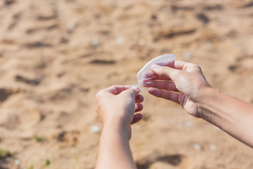 Woman holds a white feather of a seagull in hand. Symbol of lightness and fragility.