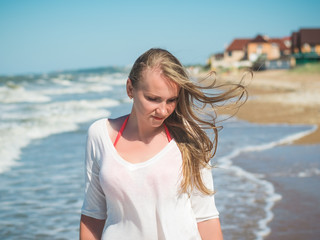 Beautiful woman with fluttering on the wind hair near the agitated sea.