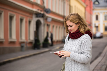 Fototapeta premium A woman looking at phone on a street in a European city
