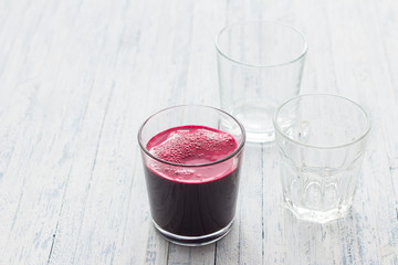 Fresh beet juice in a glass on a light blue background, selective focus. Healthy detox diet