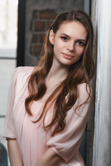 Young beautiful girl posing near the wall. Portrait of a model in a home setting