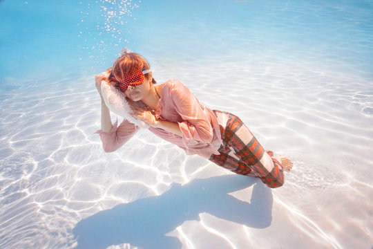 Portrait of young woman in pajamas and blindfold sleep on the pillow underwater. Businesswoman Diving in water pool, Dreaming of Holiday vacation time concept.