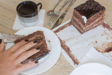 Female cutting chocolate cake, on wooden table