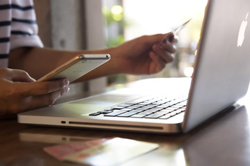 Fototapeta premium Ręce trzymając kartę kredytową, telefon komórkowy i za pomocą laptopa. Zakupy online, koncepcja rezerwacji podróży. Selektywna ostrość.