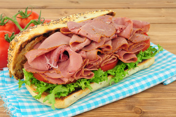 Spicy pastrami meat and salad sandwich in a seed covered bread roll isolated on a white background