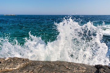White wave splashing against rocky shore
