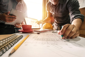 Creative architect projecting on the big drawings in the dark loft office or cafe in morning light
