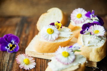 Obraz na płótnie Canvas Sandwich with herb and edible flowers butter on marble cutting board. Healthy food.