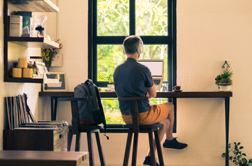 man in casual cloths sitting at coffee shop using his laptop computer