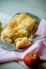 A fresh baked apple pie and a cut piece of pie are sprinkled with powdered sugar, close-up view