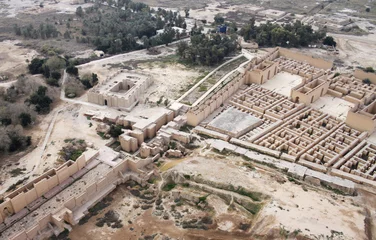 Foto op Plexiglas Rudnes Gerestaureerde ruïnes van het zuidelijke paleis van Nebukadnezar in het oude Babylon, Irak aan de rechterkant. Ruïnes van het noordelijke paleis beschadigd door de Amerikaanse bezetting aan de linkerkant. Voorbij Processional Street is de Ninmah-tempel.