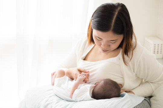 Asian mother holding her newborn baby boy and breastfeeding, Milk mother for child concept