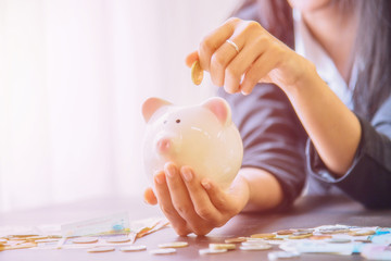 Piggy bank in hand with cash pile.