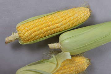 Fresh corn on cobs on texture background, closeup, top view