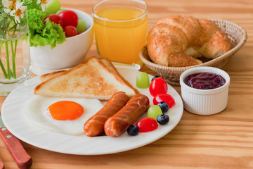 Homemade breakfast with sunny side up fried egg toast sausage fruits vegetable strawberry jam and orange juice in top view with copy space.Delicious homemade american breakfast concept for background