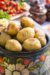 Baked whole potatoes in a pot, painted in Russian folk style.Table with food decorated in Russian folk style.