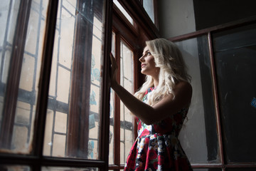 beautiful blonde poses near old windows in a building