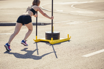 woman pushing sled at gym. African woman doing intense physical workout in gym