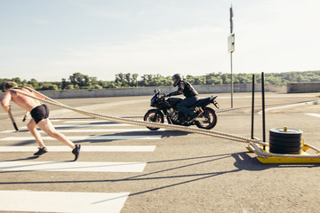 sled push man pushing weights workout and competing with motorcycle