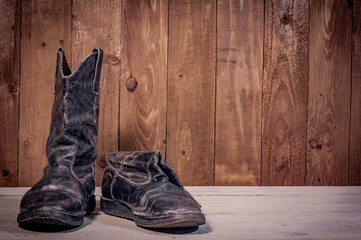 Old leather boots on dirt wooden background  