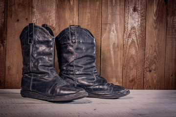 Old leather boots on dirt wooden background  