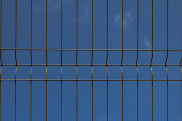 close up picture of cage fence against blue sky  