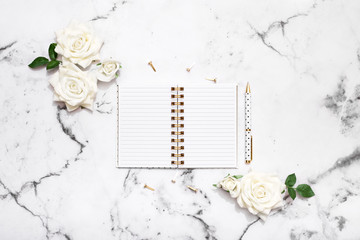 Wedding planning flat lay with notebook, pen and white roses