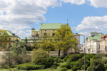 Fototapeta na wymiar Spring trees and shrubs in the Warsaw Old Town under the blue sky with clouds