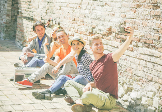 Group of multiracial friends taking a selfie with a mobile smartphone camera