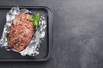 Baking tray with raw turkey meatloaf on table