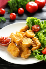 Tasty nuggets and small bowl with sauce for chicken on plate