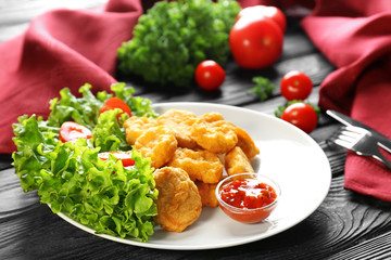 Tasty nuggets and small bowl with sauce for chicken on plate