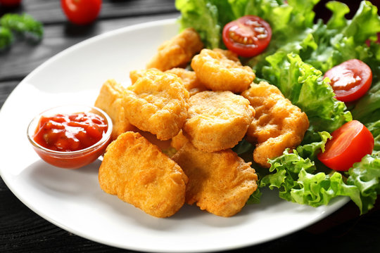 Tasty nuggets and small bowl with sauce for chicken on plate