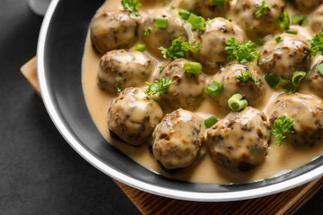 Frying pan with delicious meatballs in sauce on table